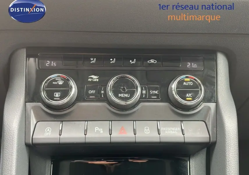 Vue rapprochée de la console centrale du Skoda Karoq blanc glacier 2025, mettant en valeur les commandes de climatisation et d'assistance.