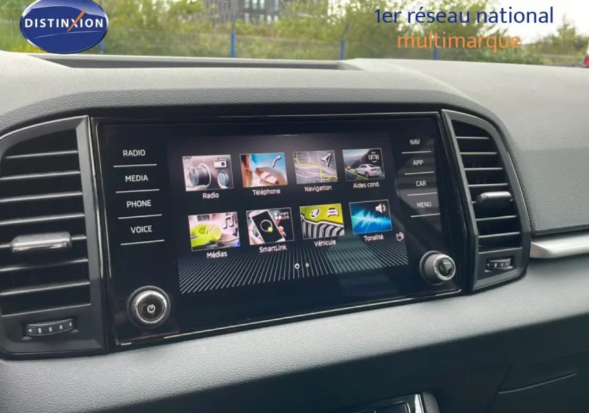 Vue rapprochée de l'écran tactile central du Skoda Karoq blanc glacier, affichant les options multimédias et de navigation.