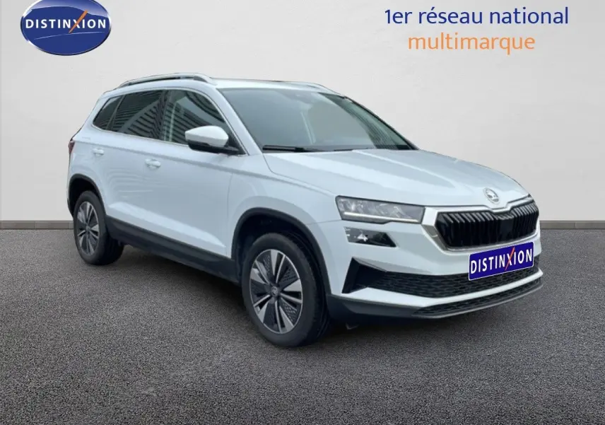 Vue 3/4 avant droit d’un Skoda Karoq blanc glacier avec calandre noire et jantes bi-ton.