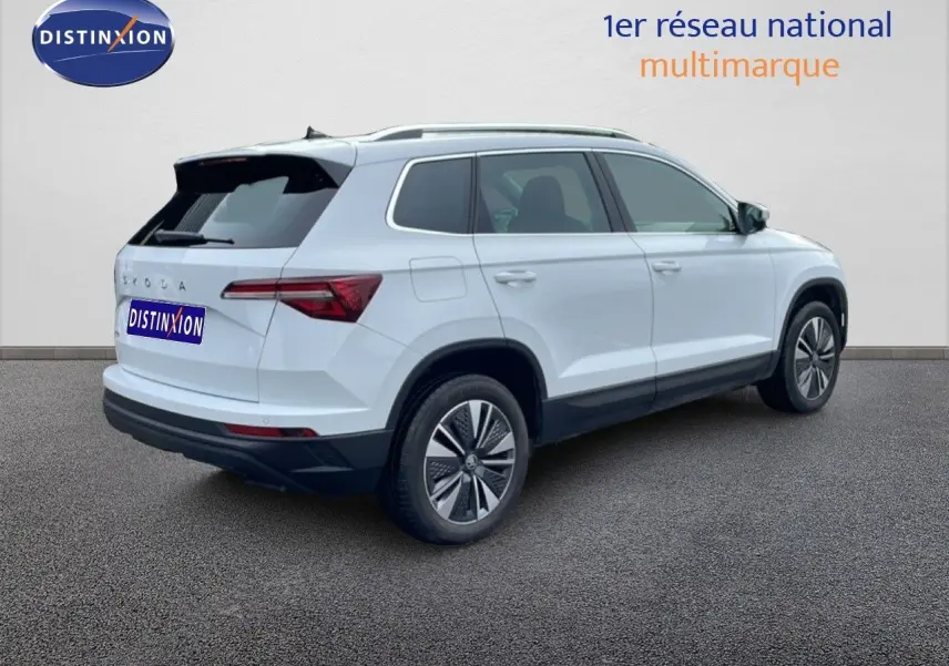 Vue 3/4 arrière droite du Skoda Karoq blanc glacier avec jantes bi-ton et toit noir contrasté.