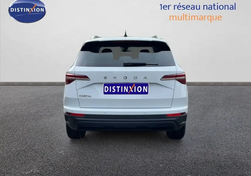 Vue arrière d'un Skoda Karoq blanc glacier 2025, avec feux arrière LED et logo SKODA visible.