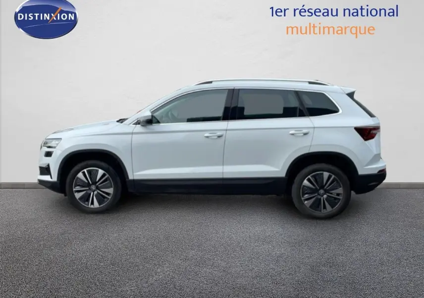 Profil droit du SUV SKODA KAROQ blanc glacier 2025 avec jantes alliage bicolores et vitres teintées.