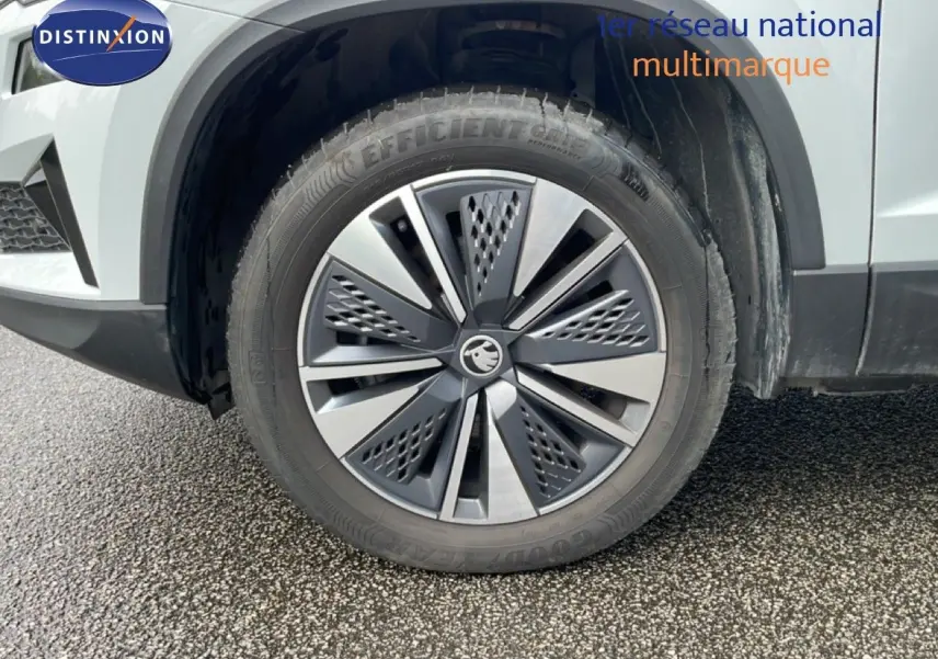Gros plan sur la roue avant droite du Skoda Karoq blanc glacier, mettant en valeur la jante alu biton au design moderne.