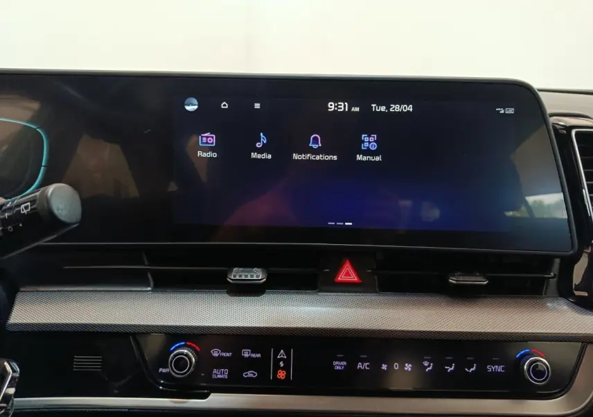 Tableau de bord central tactile et commandes climatisation du Kia Sportage blanc, vue intérieure frontale.