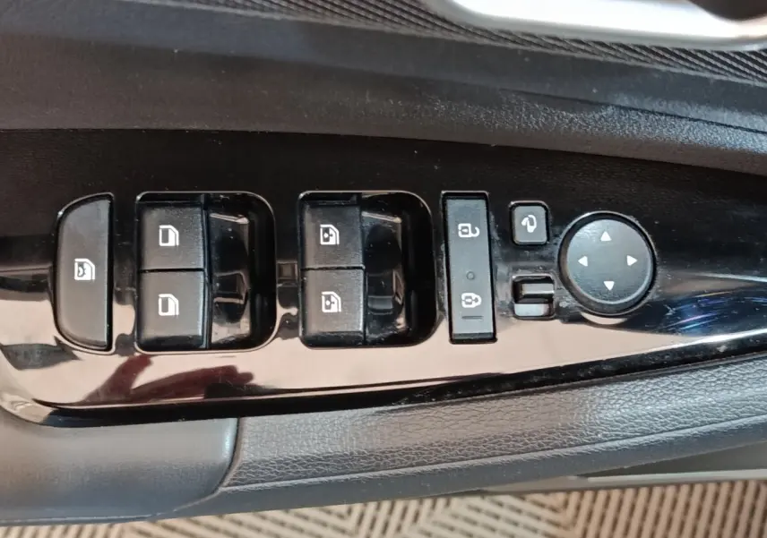 Gros plan sur les commandes de lève-vitres et rétroviseurs côté conducteur du Kia Sportage blanc 2022.