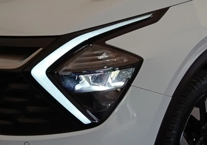 Gros plan sur le phare avant droit blanc du KIA SPORTAGE 2022 avec éclairage LED en forme de flèche.
