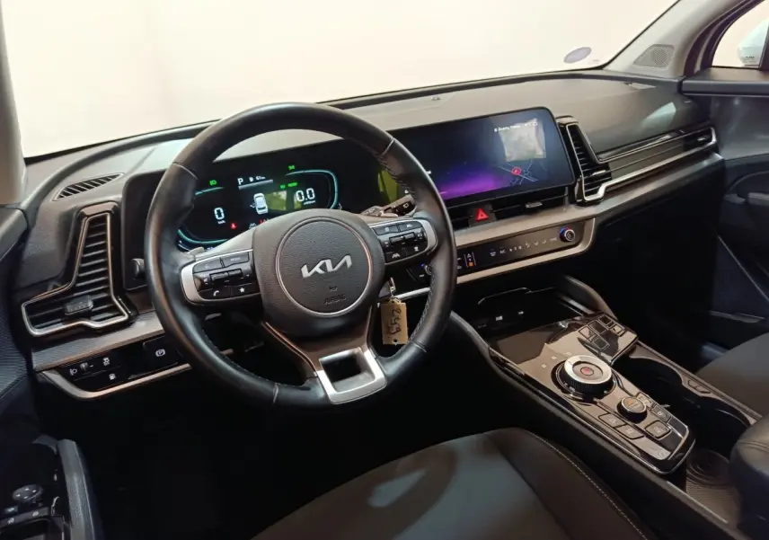 Vue intérieure côté conducteur du tableau de bord et volant cuir noir du Kia Sportage hybride rechargeable 2022.