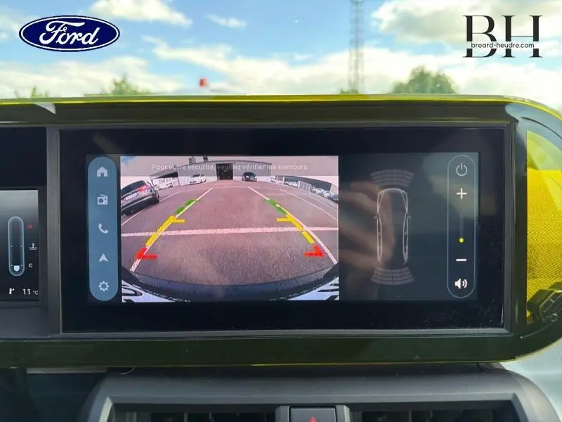 Écran tactile intérieur montrant la caméra de recul et les aides au stationnement d'une Fiat Grande Panda noire.