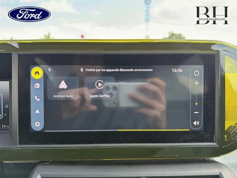 Écran tactile central affichant Android Auto et Apple CarPlay dans un Ford avec tableau de bord jaune vif.