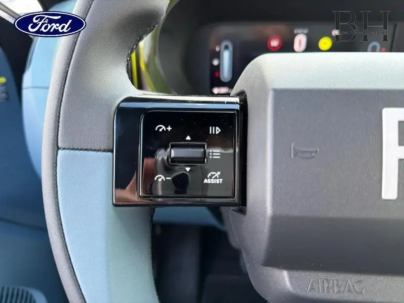 Gros plan sur le volant bleu et noir de la Fiat Grande Panda 2025, montrant les commandes d’assistance et le tableau de bord numérique.
