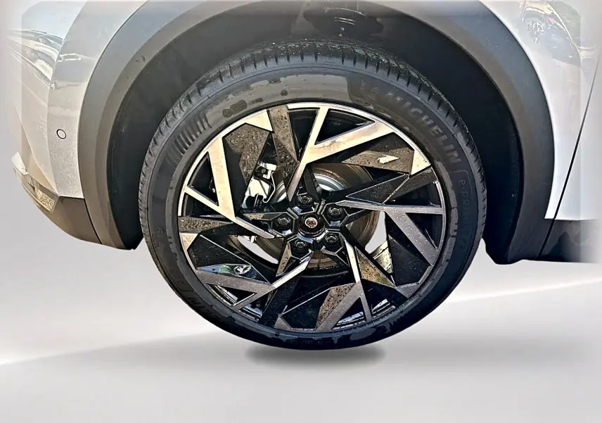 Gros plan sur la roue avant gauche du Renault Symbioz gris rafale, jante alu au design géométrique noir et argent.