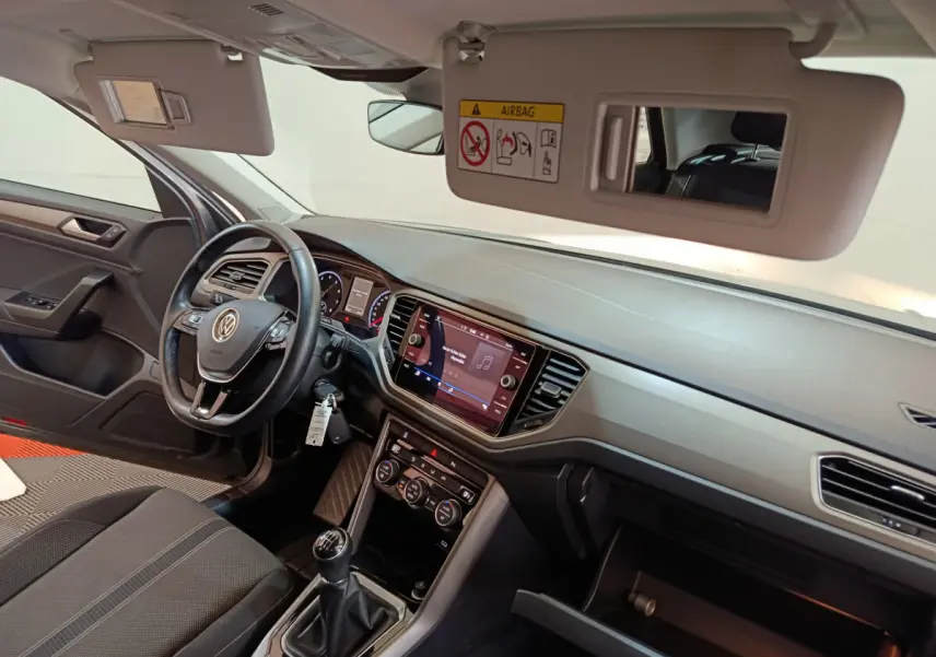 Intérieur Volkswagen T-Roc 2021 côté conducteur, tableau de bord noir avec écran tactile et boîte manuelle visible.