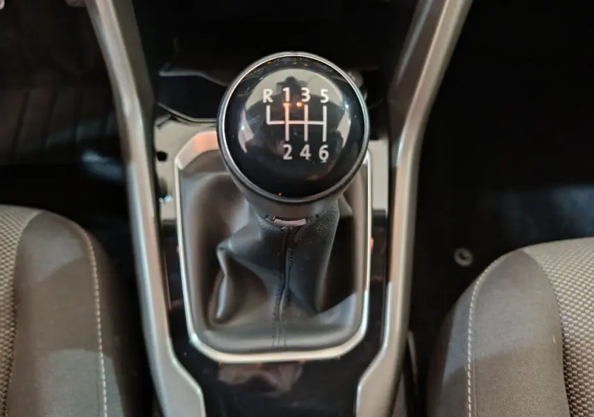 Le levier de vitesses manuel noir du Volkswagen T-Roc 1.0 TSI 110 Lounge Business vu de dessus entre les sièges gris.