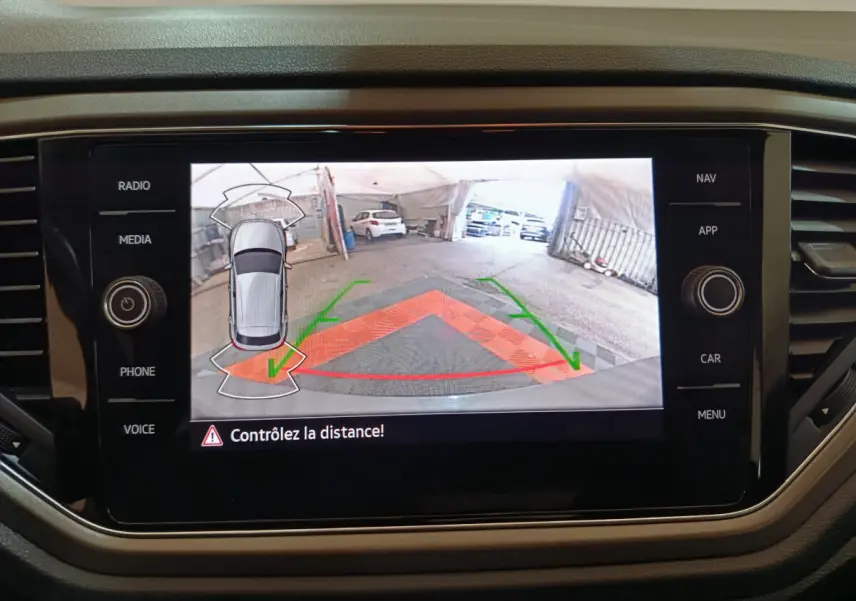 Écran tactile intérieur du Volkswagen T-Roc gris foncé montrant la caméra de recul avec guidage de trajectoire coloré.