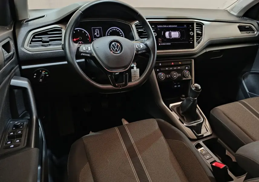 Intérieur du Volkswagen T-Roc gris foncé, vue du poste de conduite avec volant cuir et écran tactile central.