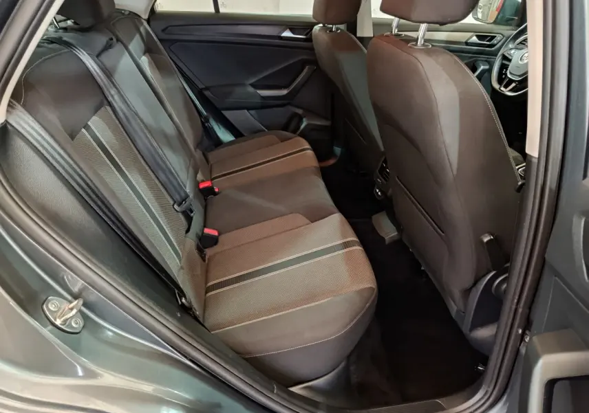 Vue intérieure arrière droite du Volkswagen T-Roc gris foncé, montrant la banquette tissu avec bandes centrales contrastées.