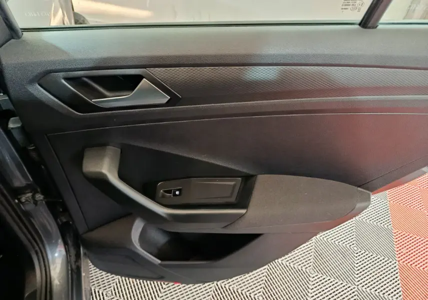 Vue rapprochée de la porte avant gauche grise foncée du Volkswagen T-Roc 2021 avec poignée et commande de vitre électrique.