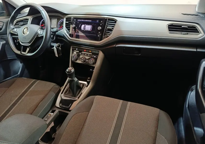 Intérieur du Volkswagen T-Roc 2021 vue côté conducteur, volant cuir, tableau de bord avec écran tactile et boîte manuelle.
