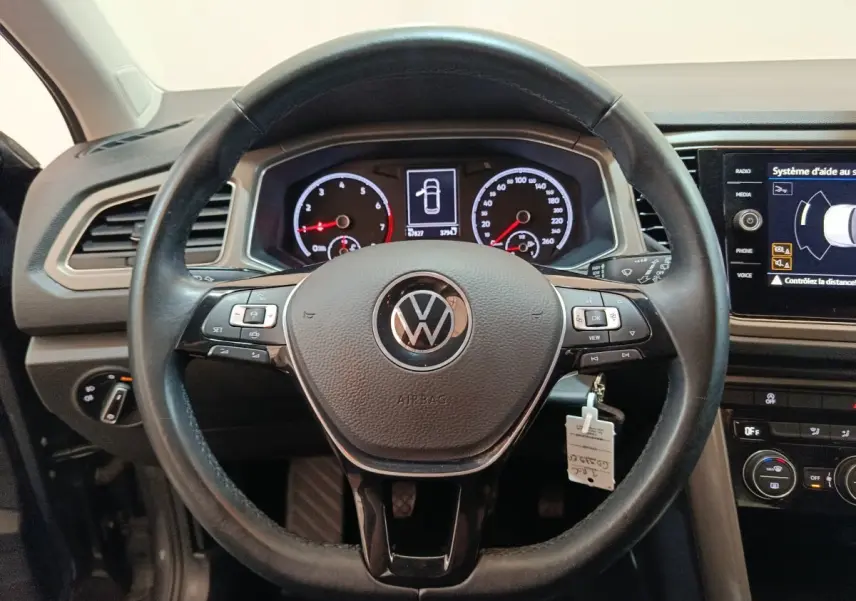 Vue frontale du volant cuir noir du Volkswagen T-Roc 2021 avec tableau de bord digital et écran tactile latéral.