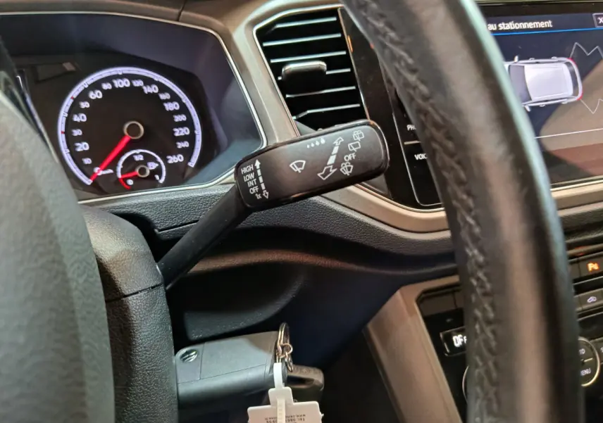 Vue intérieure rapprochée du volant et du commodo d’essuie-glace du Volkswagen T-Roc 2021, avec tableau de bord et écran tactile visibles.