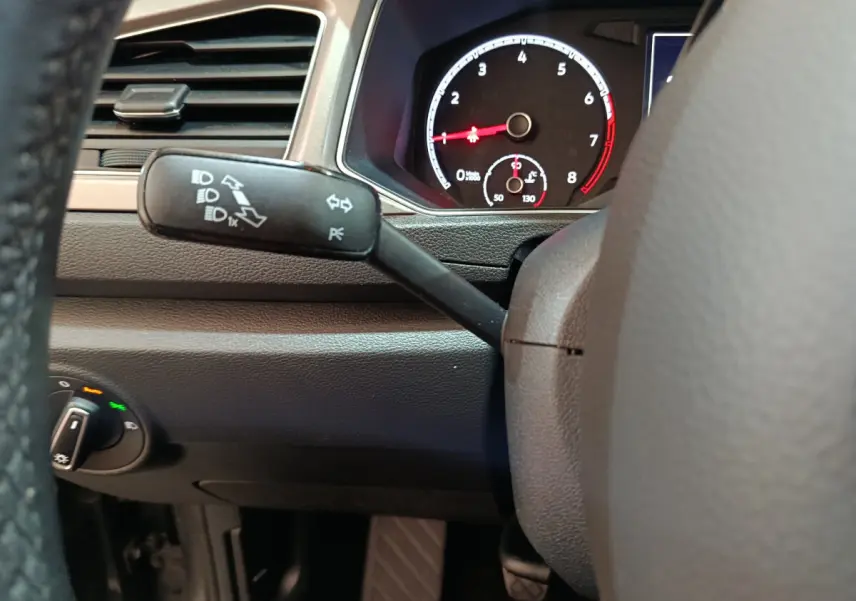 Détail du tableau de bord et du commodo gauche du Volkswagen T-Roc 1.0 TSI gris foncé, avec compte-tours visible.