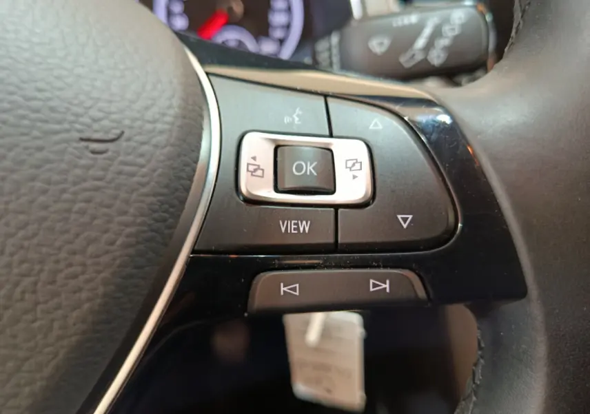 Gros plan sur les commandes multifonctions du volant cuir noir du Volkswagen T-Roc 2021 gris foncé.