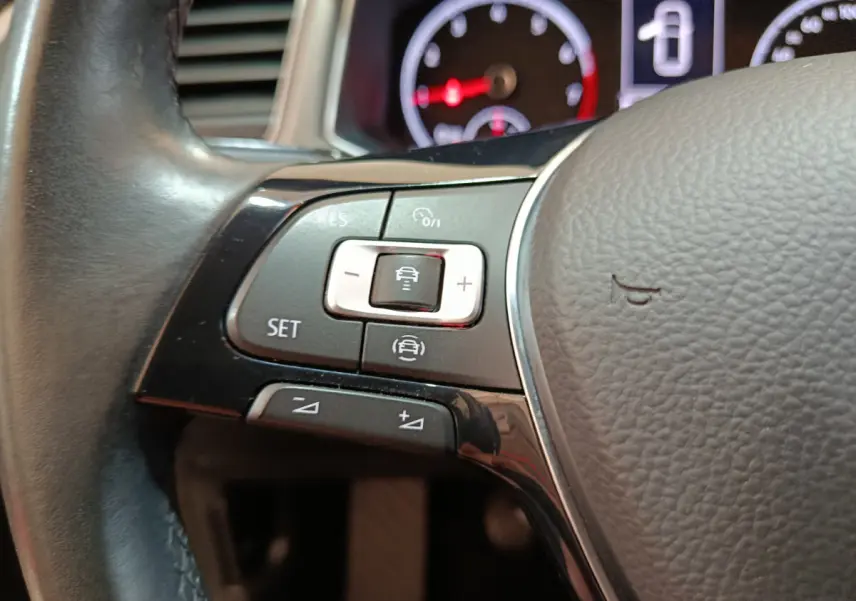 Gros plan sur les commandes du volant cuir du Volkswagen T-Roc 2021, avec tableau de bord numérique en arrière-plan.