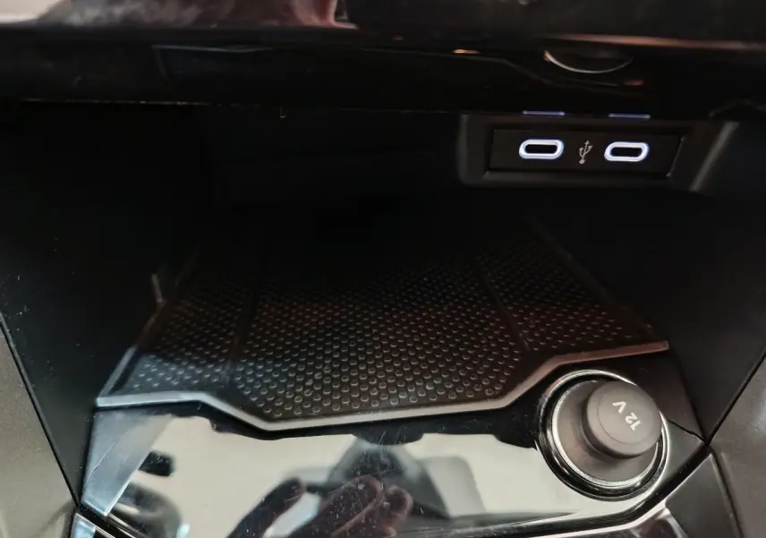 Prise 12V et ports USB doubles dans la console centrale du Volkswagen T-Roc 1.0 TSI gris foncé, vue intérieure rapprochée.