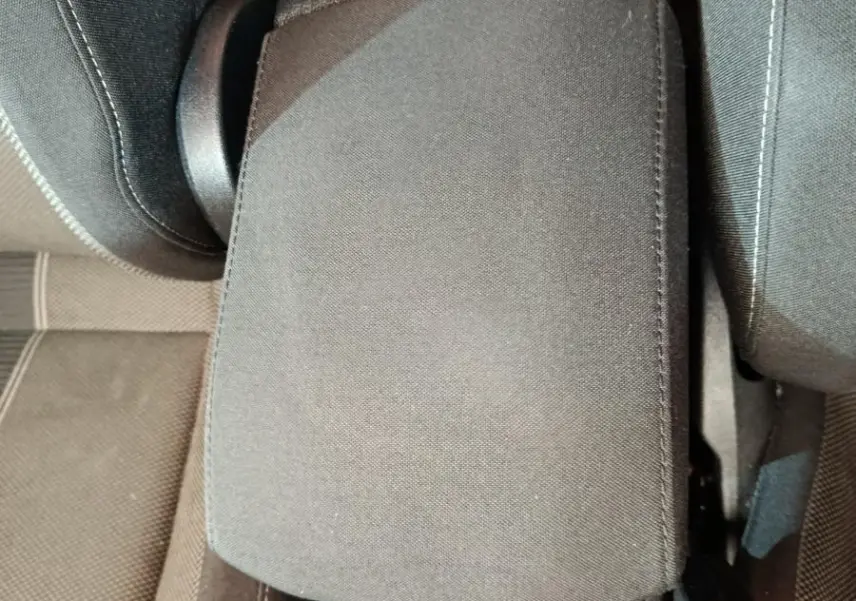 Vue plongeante sur l'accoudoir central gris foncé et la console entre les sièges avant du Volkswagen T-Roc 2021.