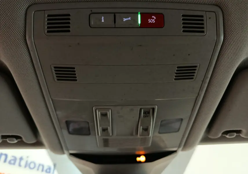 Vue rapprochée du plafonnier intérieur gris clair du Volkswagen T-Roc 2021 avec boutons SOS et éclairage d'ambiance allumé.