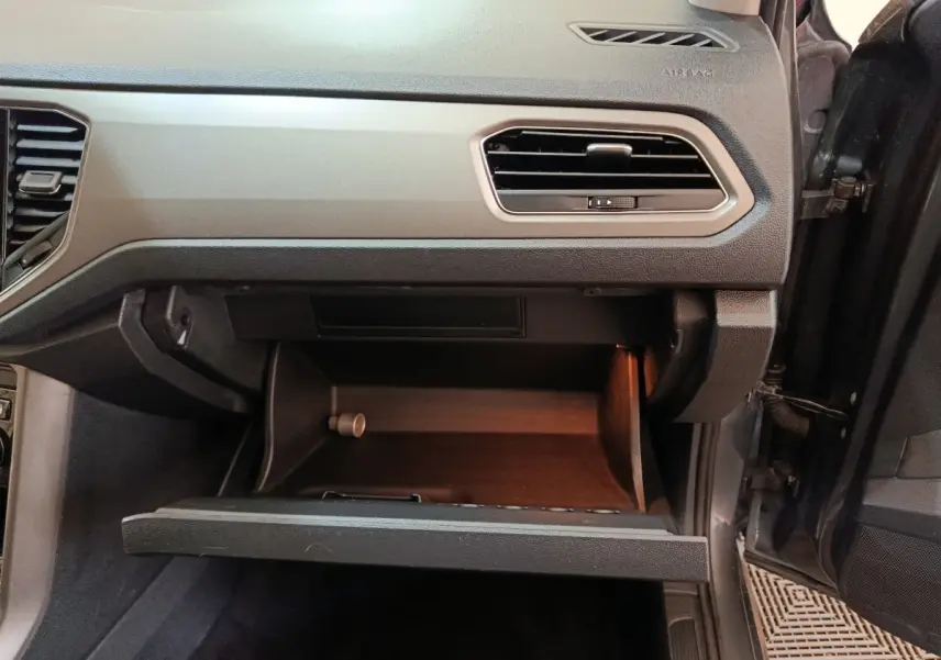 Vue intérieure côté passager du tableau de bord gris foncé et boîte à gants ouverte du Volkswagen T-Roc 2021.