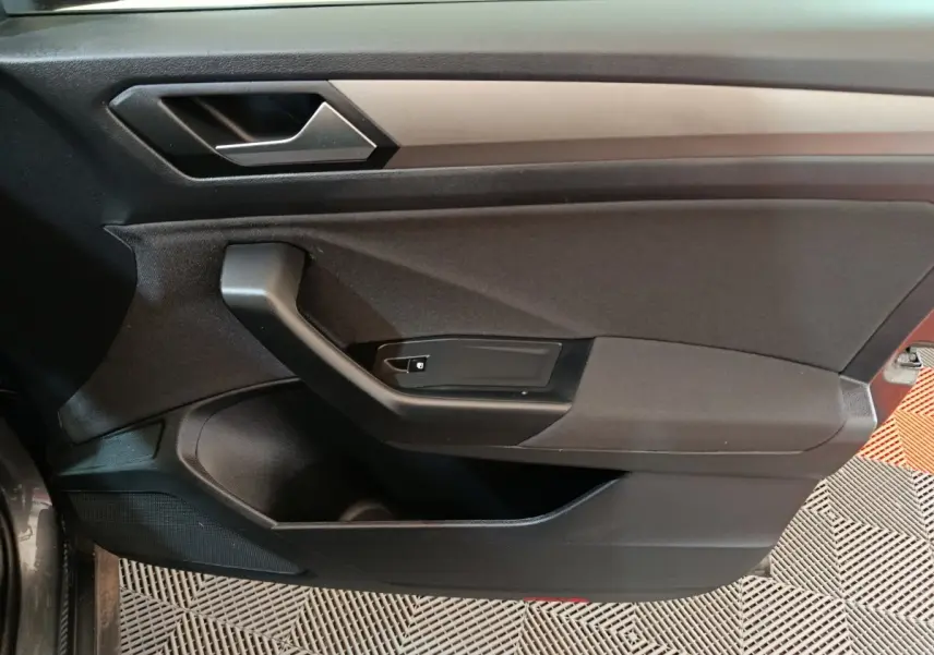 Intérieur côté gauche de la porte avant d'un Volkswagen T-Roc gris foncé, avec poignée et commandes de verrouillage.