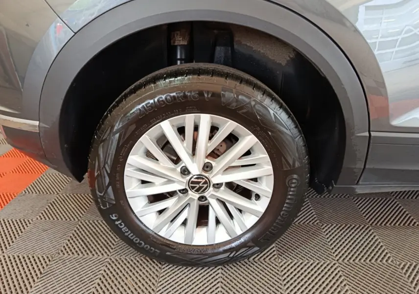 Gros plan sur la roue avant gauche gris foncé du Volkswagen T-Roc 1.0 TSI 110 Lounge Business avec jante alliage blanche.