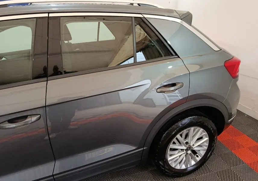 Vue côté droit arrière du Volkswagen T-Roc gris foncé mettant en valeur la roue et les lignes de caisse.