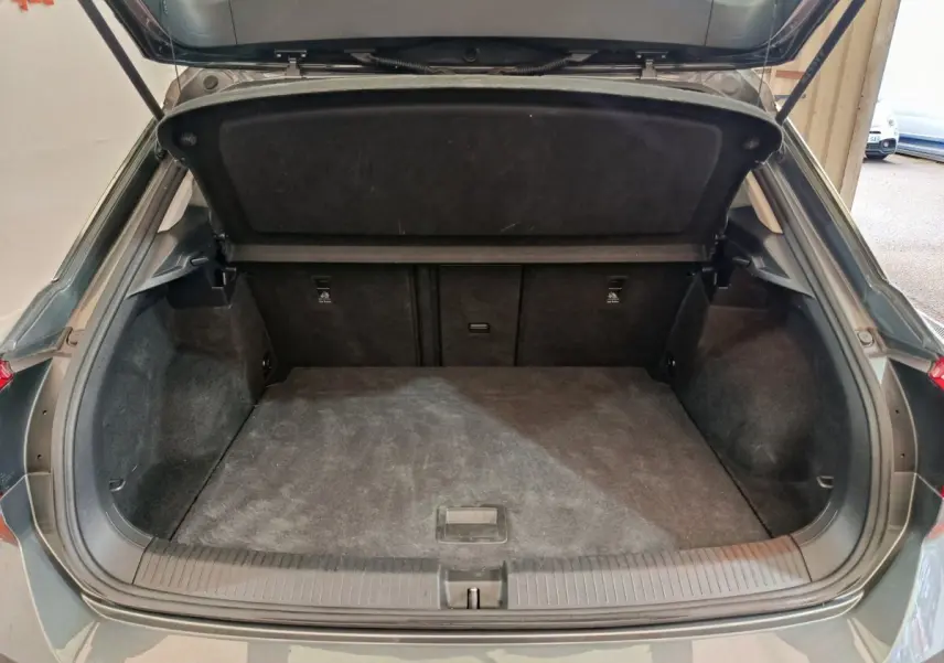Coffre ouvert vu de l'arrière d'un Volkswagen T-Roc gris foncé, montrant un espace de chargement propre et spacieux.
