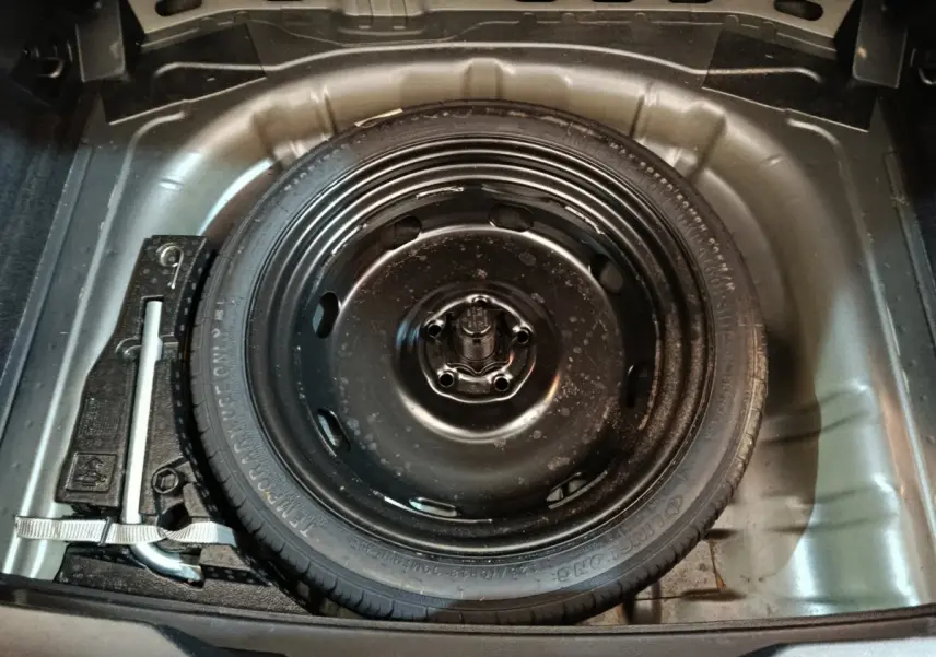 Vue rapprochée de la roue de secours noire dans le coffre gris foncé du Volkswagen T-Roc 1.0 TSI 110 Lounge Business 2021.