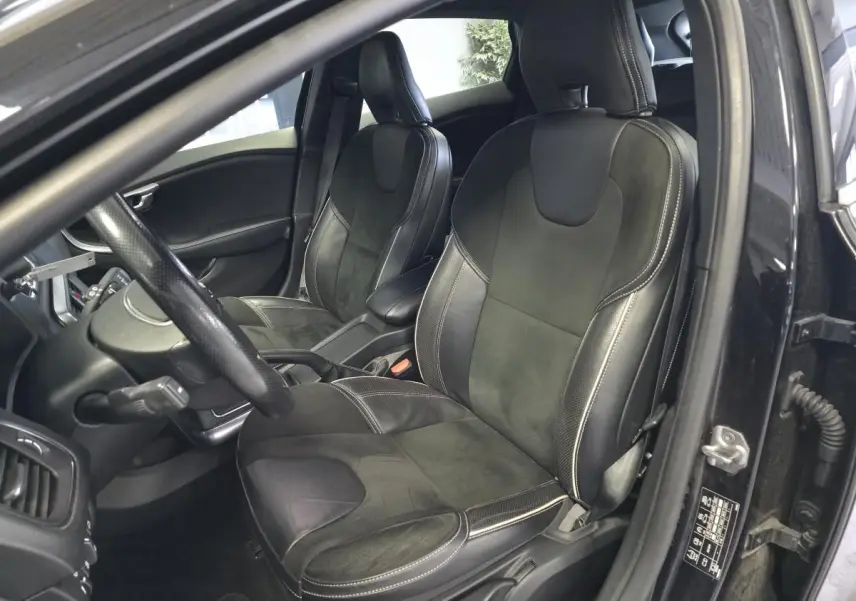 Vue intérieure côté conducteur d'une Volvo V40 D2 R-Design 2019 noire, sièges sport cuir et alcantara avec surpiqûres beige.