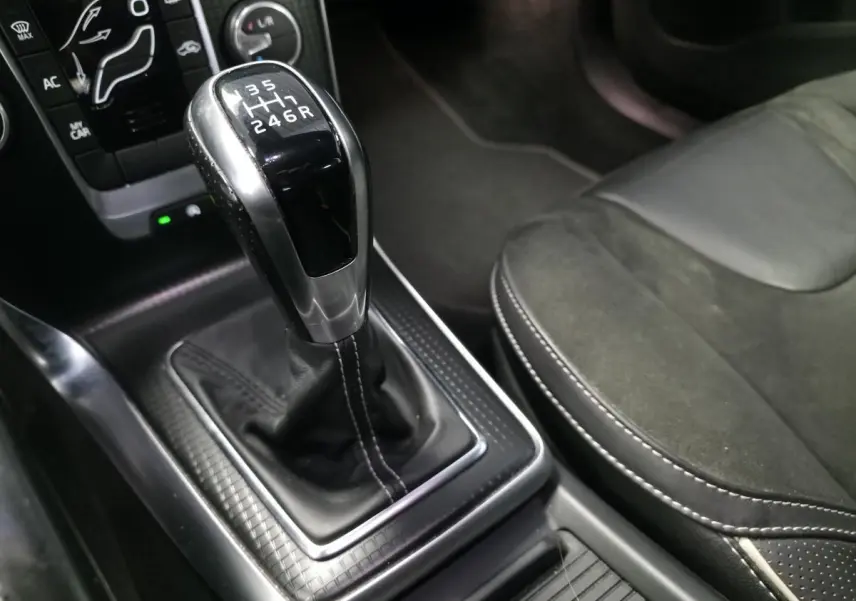 Levier de vitesses manuel en cuir perforé avec surpiqûres beige dans l'habitacle noir du Volvo V40 R-Design.