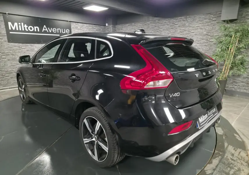 Vue 3/4 arrière droite d'une Volvo V40 D2 R-Design noire avec jantes alliage IXION et double sortie d'échappement chromée.