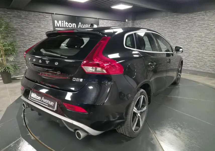 Vue 3/4 arrière droite d'une Volvo V40 D2 noire avec jantes alliage et double sortie d'échappement chromée.