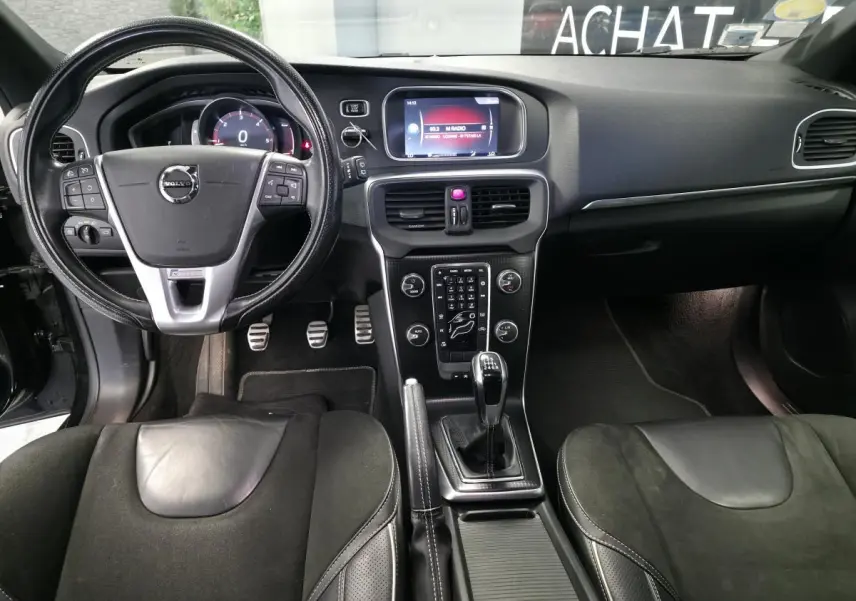 Vue intérieure avant de la Volvo V40 D2 R-Design 2019, volant cuir perforé, levier manuel et console centrale noire.