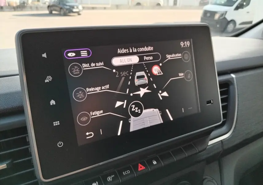 Écran tactile intérieur du Nissan Primastar 2025 montrant les aides à la conduite avec vue sur tableau de bord noir.