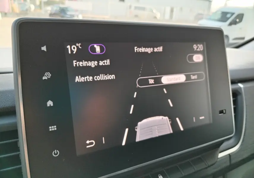 Écran tactile intérieur du Nissan Primastar 2025 montrant l'alerte collision et freinage actif à 19°C.