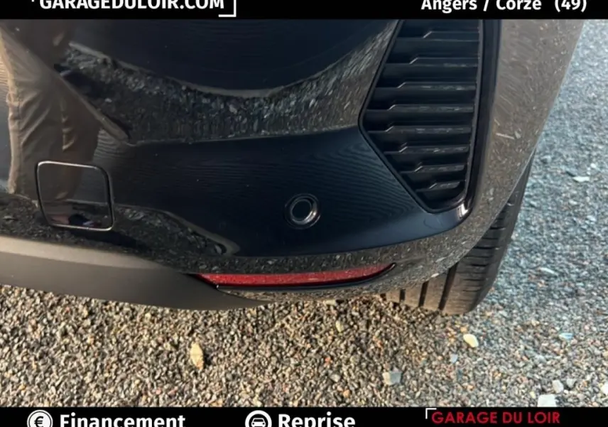 Gros plan sur le pare-chocs arrière droit noir de la Renault Clio 2025 avec capteur de stationnement et feu réfléchissant rouge.