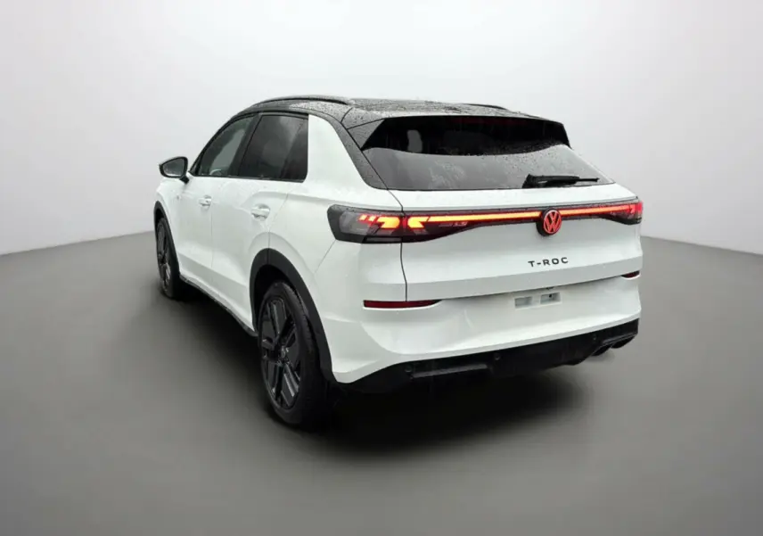 Volkswagen T-Roc blanc toit noir en 3/4 arrière droit avec feux arrière allumés et jantes noires.