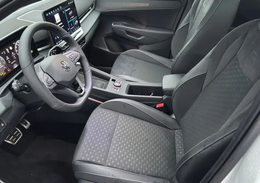 Vue intérieure côté conducteur du Volkswagen T-Roc 2026, sièges tissu noir avec surpiqûres et volant cuir multifonctions.