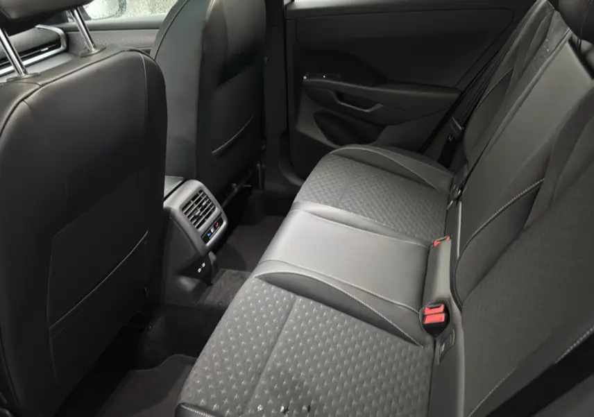 Vue intérieure arrière côté droit du Volkswagen T-Roc 2026, sièges tissu noir avec surpiqûres grises et aérateurs centraux.