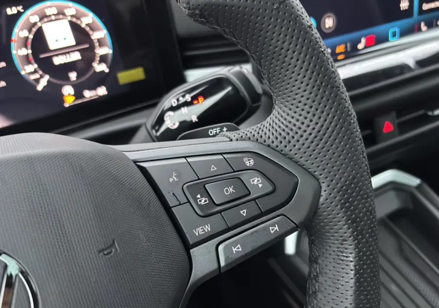 Gros plan sur le volant cuir perforé du Volkswagen T-Roc 2026 avec commandes multifonctions et tableau de bord numérique.