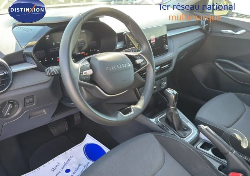 Vue intérieure côté conducteur de la Skoda Fabia 2025 avec volant multifonction, tableau de bord digital et sellerie tissu noir.