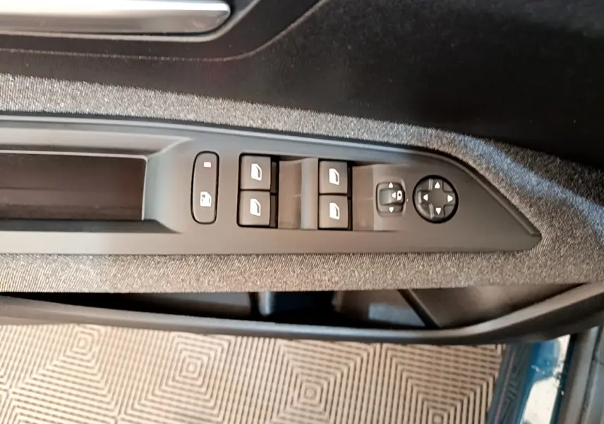 Vue rapprochée des commandes de lève-vitres et rétroviseurs sur la porte côté conducteur d’un Peugeot 3008 bleu.